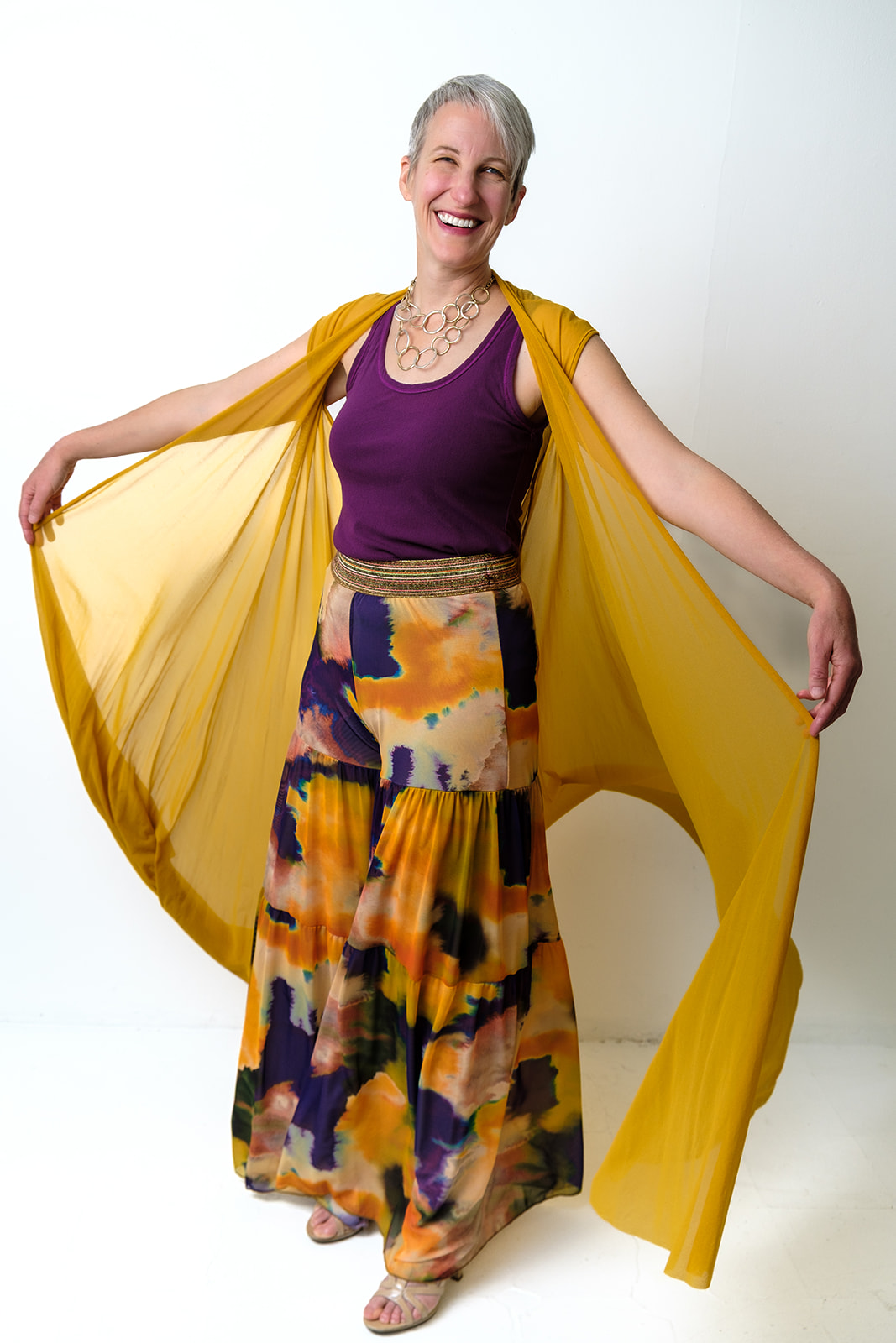 Kristen Peairs smiling with a flowing gold wrap